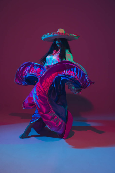 Fabulous Cinco de Mayo female dancer on purple studio background in neon light - Foto, afbeelding