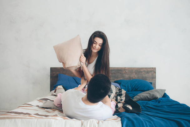 A loving couple are lying on the bed. Bright and cozy bedroom. Family comfort and love - 写真・画像
