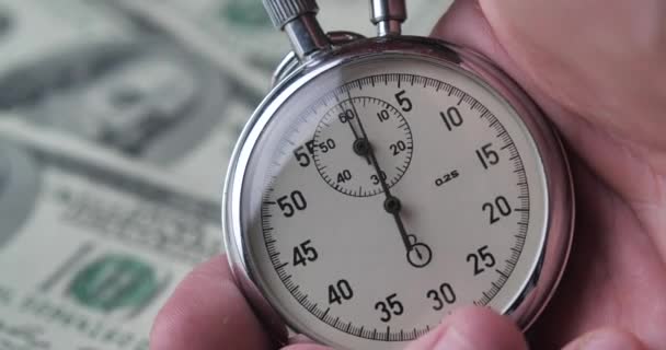 Κοντινό πλάνο ενός ατόμου που ξεκινά ένα χρονόμετρο στο υπόβαθρο των χρημάτων δολάρια. Ο χρόνος είναι χρήμα. Έννοια προθεσμίας. - Πλάνα, βίντεο