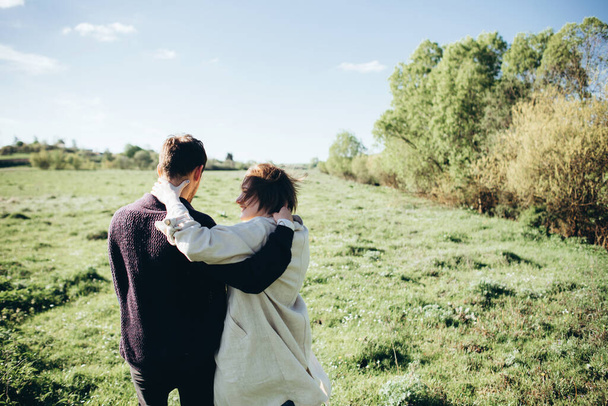 Casal abraço desfrutando de tempo ensolarado em campo
 - Foto, Imagem