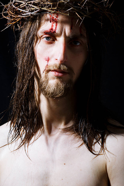 Jesus Christ with long hair and crown of thorns, blood on forehead. - Foto, imagen