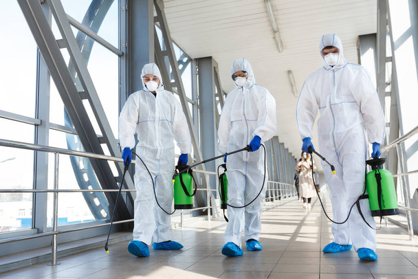 Personel medyczny noszący odzież ochronną dezynfekuje miejsce publiczne - Zdjęcie, obraz