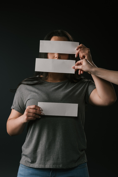 Front view of young size plus woman hiding face under empty cards on black background - Фото, изображение