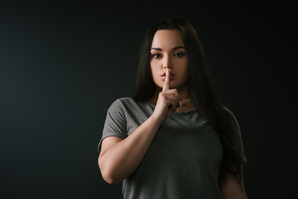 Front view of plus size girl with silence gesture isolated on black - Photo, Image
