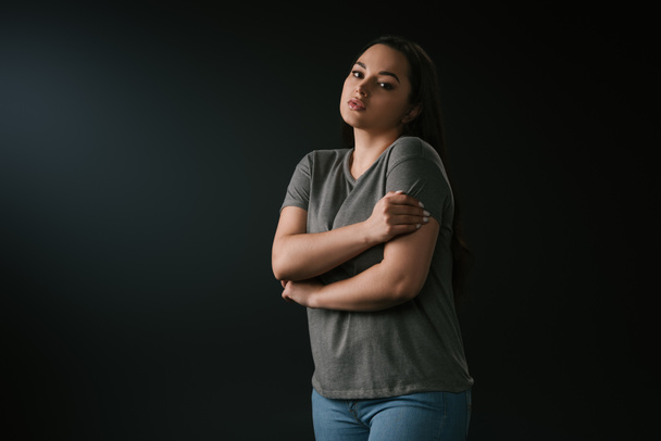 Lonely plus size girl hugging herself on black background  - Photo, Image