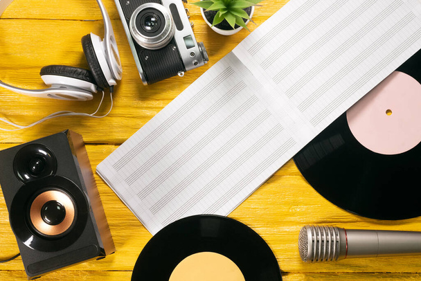 Retro vinyl record, music book, microphone and speakers on yellow flat lay background. - 写真・画像