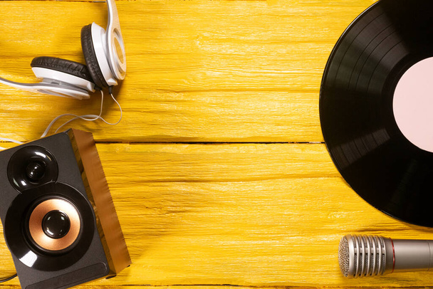Vinyl record, microphone, headphones and loudspeaker on yellow flat lay background with copy space. - Fotó, kép