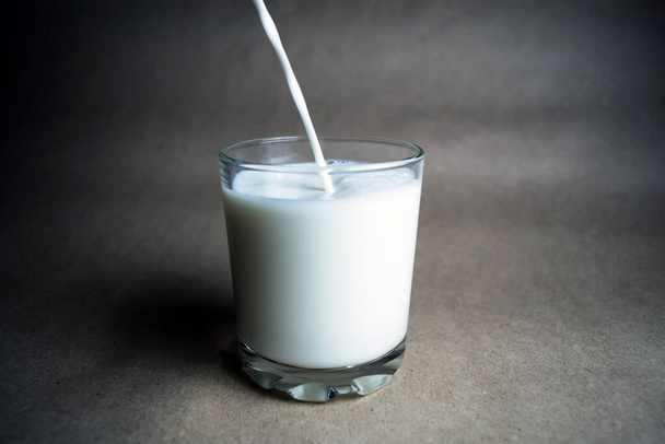 Le processus de verser du lait dans un verre. Fond beige
 - Photo, image