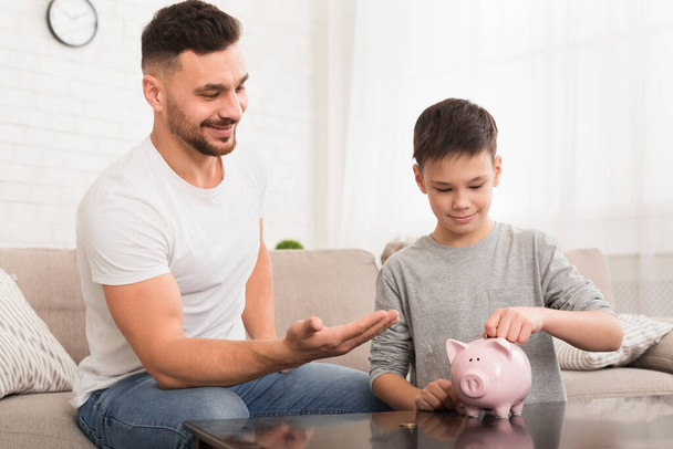 Papá le enseña a su hijo a ahorrar dinero en casa
 - Foto, imagen