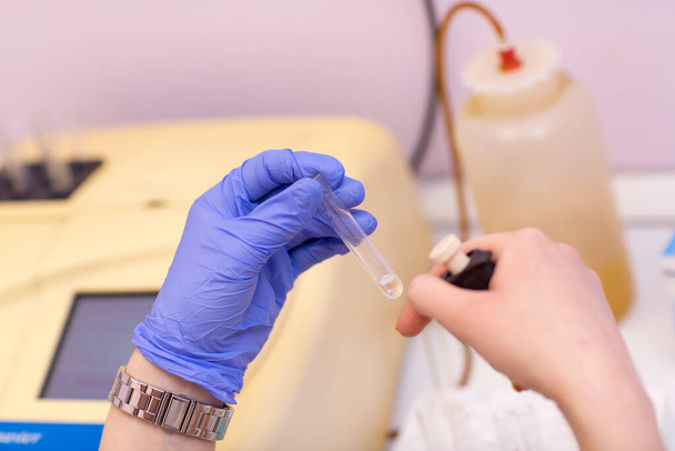 Assistente de laboratório em laboratório médico detém tubo de teste com sangue e plasma em sua mão e fazendo análise
. - Foto, Imagem