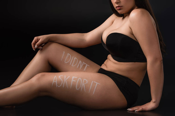 Cropped view of plus size model with lettering I Did not Ask For It on body on black background - Photo, Image