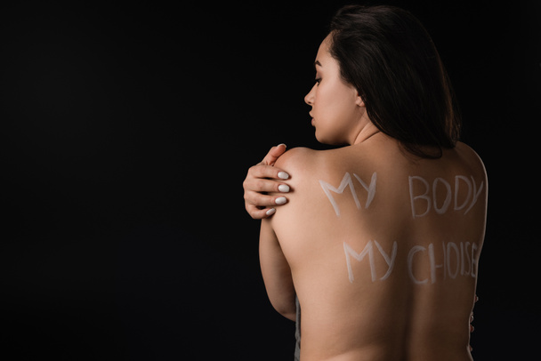 Rückansicht des schönen Plus-Size-Modells mit Schriftzug My Body My Choice auf nacktem Rücken isoliert auf schwarz  - Foto, Bild