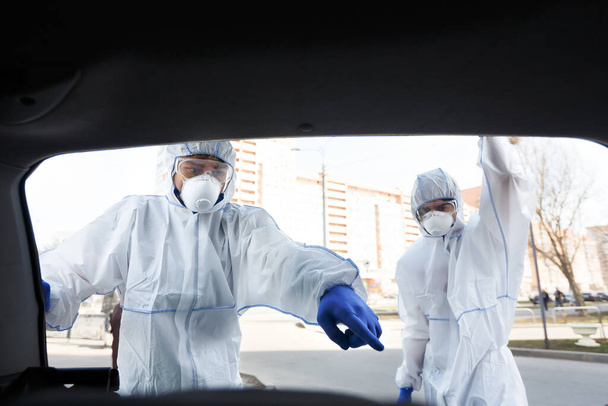 コロナウイルスのスーツ姿の男が化学物質の消毒を指差す - 写真・画像