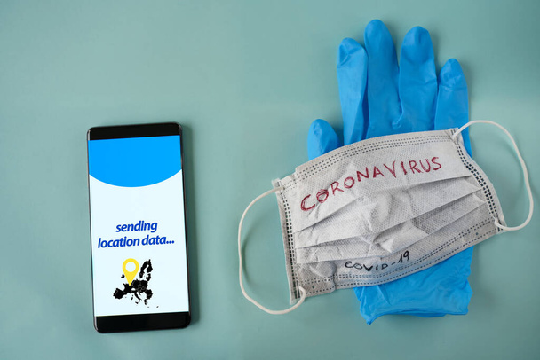 Máscara médica blanca, globo azul y teléfono con software de vigilancia de ubicación en pantalla aislada sobre fondo cian
 - Foto, imagen