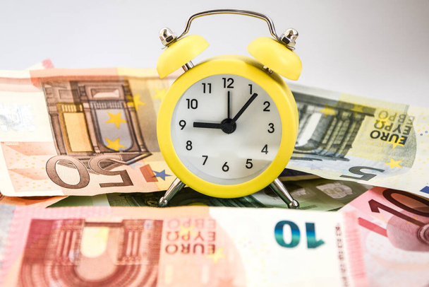 Tempo é dinheiro. Estimativa europeia do seu tempo. Evro, despertador e papel-moeda europeu, sobre fundo branco. Conceito de negócio, tempo é dinheiro, relógio de alarme para notas de euro
 - Foto, Imagem
