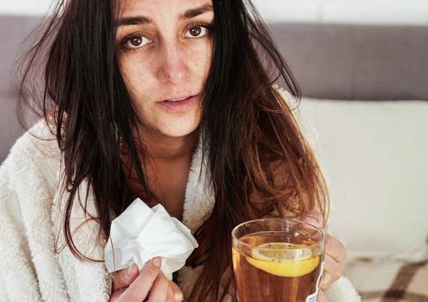 Blurred young woman is feeling bad and sick lying in the bed at home. Girl has symptoms of respiratory viral infection, fever, cough. Coronavirus covid-19 epidemic concept. - Photo, Image