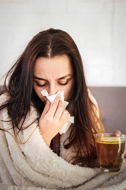 Blurred woman is feeling bad and sick at home. Girl has symptoms of respiratory viral infection. Woman is drinking hot tea. Coronavirus covid-19 epidemic pandemic concept. - Photo, Image