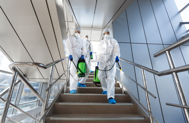 Pracownicy rządowi w kombinezonach ochronnych dezynfekujących schody - Zdjęcie, obraz