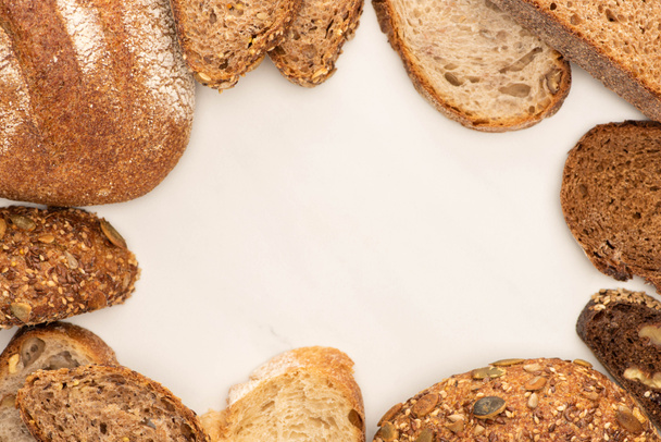 top view of fresh brown bread slices and loaves on white background - Foto, afbeelding