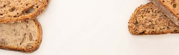 vista superior de fatias de pão de grão inteiro fresco no fundo branco com espaço de cópia, tiro panorâmico
 - Foto, Imagem