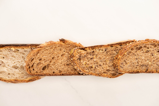 top view of whole grain bread slices in line on white background - Fotoğraf, Görsel