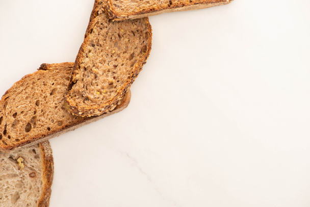 vista superior de fatias de pão de grão integral no fundo branco com espaço de cópia
 - Foto, Imagem