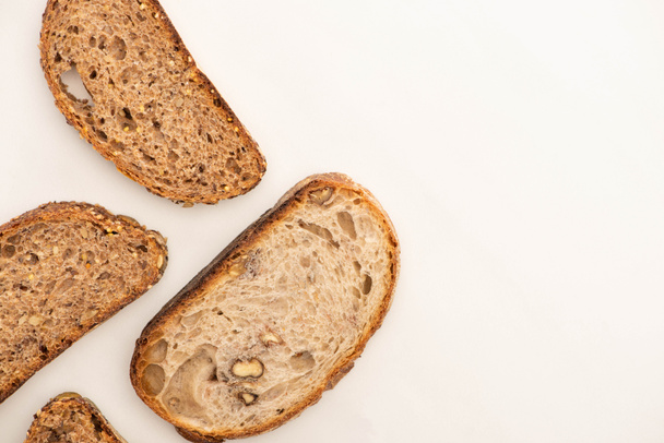 vista superior de saborosas fatias de pão de grão inteiro no fundo branco com espaço de cópia
 - Foto, Imagem
