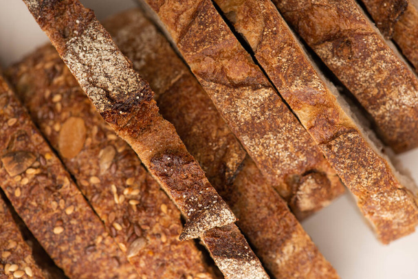 κορυφαία άποψη των νόστιμων φέτες ψωμί ολικής άλεσης με κρούστα σε λευκό φόντο - Φωτογραφία, εικόνα