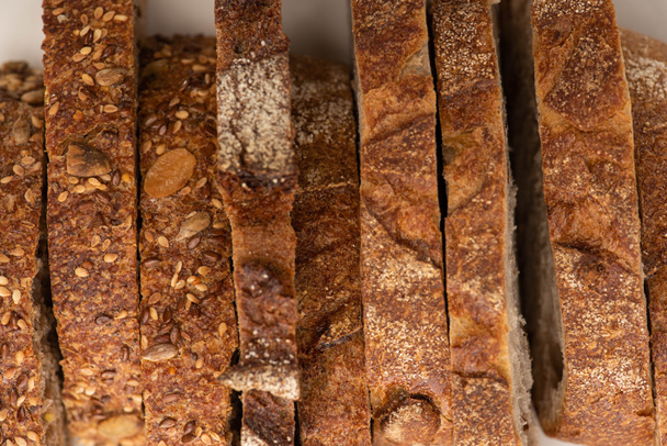 вид сверху на вкусный цельнозерновой хлеб ломтики с коркой на белом фоне
 - Фото, изображение