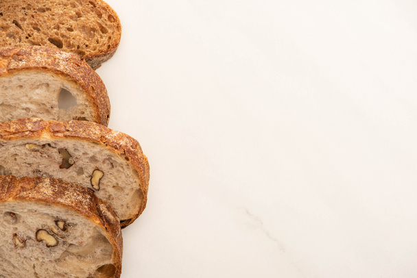 vrchní pohled na čerstvé plátky celozrnného chleba na bílém pozadí s kopírovacím prostorem - Fotografie, Obrázek