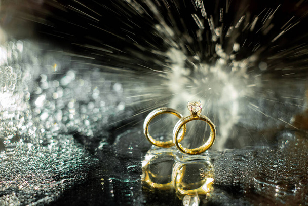 Свадебные кольца на тёмном фоне с брызгами воды и огня
. - Фото, изображение