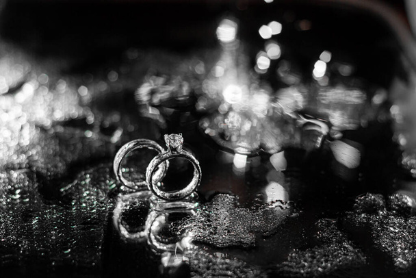 Wedding rings on a dark background with splashes of water and fire. - Photo, Image