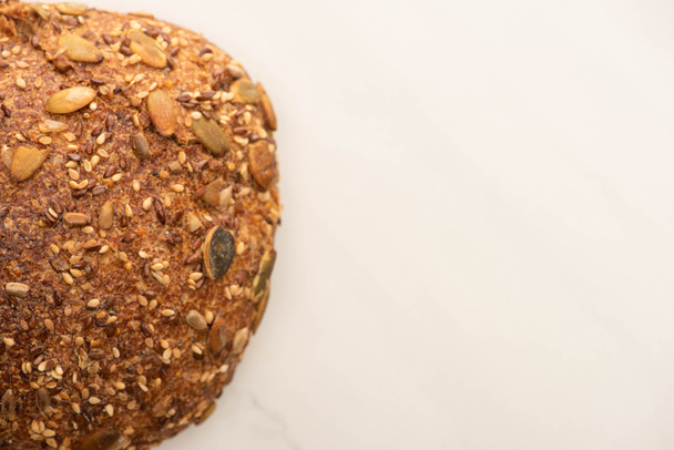 top view of fresh whole wheat bread loaf with seeds on white background with copy space - Foto, afbeelding