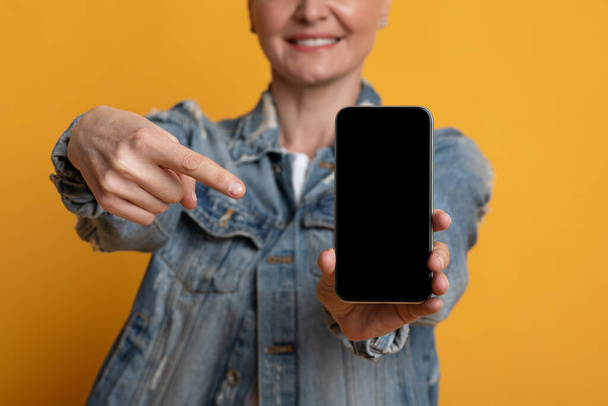 Nerozpoznatelná zralá žena ukazující na smartphone s černou prázdnou obrazovkou - Fotografie, Obrázek