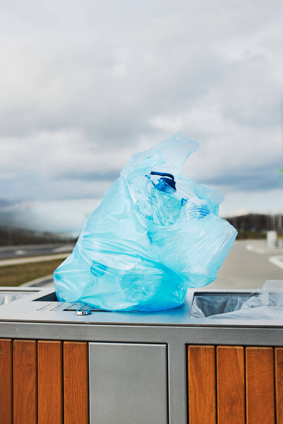 Plastic bag full of plastic waste put on outdoor trash. Plastic waste to recycling. Concept of plastic pollution and recycling plastic waste. Environmental issue. Environmental damage. Real people, authentic situations - Zdjęcie, obraz