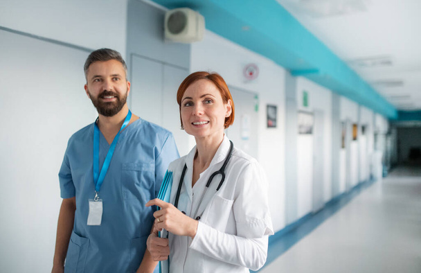 Retrato del hombre y la mujer médico caminando en el hospital, mirando a la cámara
. - Foto, imagen