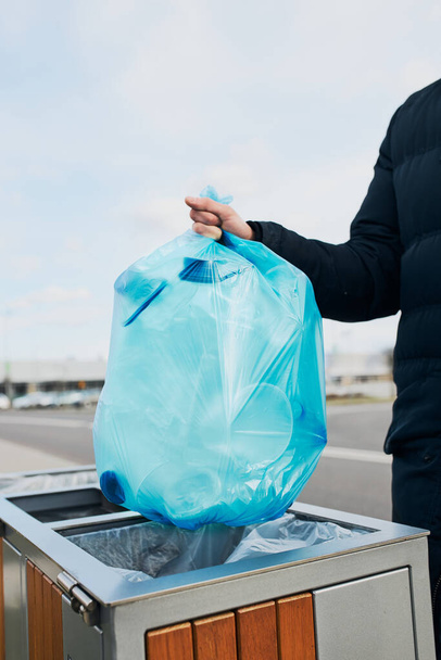 Man throwing a bag full of plastic waste to trash. Plastic waste to recycling. Concept of plastic pollution and recycling plastic waste. Environmental issue. Environmental damage. Real people, authentic situations - Fotó, kép