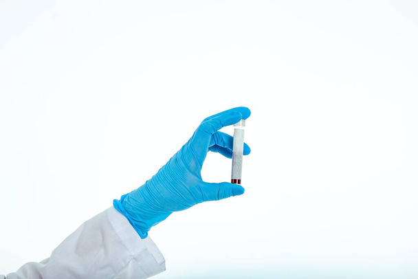 A hand in a blunted latox glove holds a blood test tube on a white background with place for text. Copy space - Foto, Bild