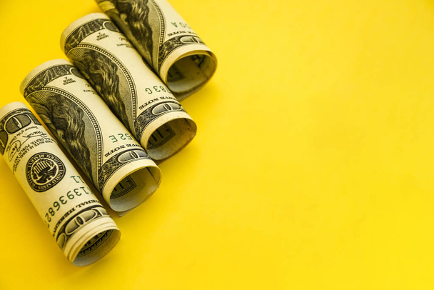 Amerikanische Dollar in Rollen. Sparkonzept auf gelbem Hintergrund mit Kopierplatz für Text, Hintergrund aus dem Dollar. Amerikanisches Geld. Das amerikanische Konto, Ersparnisse und Vermögen - Foto, Bild