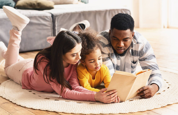 Multiracial family looking at book, stay at home - Foto, Imagem