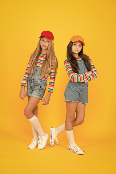 Casual luxury. Small girls in casual streetwear style on yellow background. Casual look of cute little children. Adorable kids dressed for a casual summer day outdoor - 写真・画像