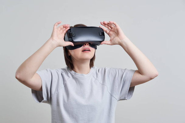 VR gözlükleriyle oynayan mutlu genç bir kadın, genç bir kızın kulaklıkla eğlendiği sanal gerçeklik konsepti, fotokopi alanı. - Fotoğraf, Görsel