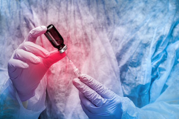 Očkovací test lékařské koncepce. Detailní záběr rukou v rukavicích s injekční stříkačkou a skleněnou lahvičkou zvýrazněnou červeně jako nebezpečí. - Fotografie, Obrázek