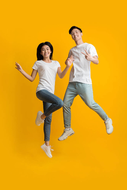 Excited asian couple of hipsters having fun over yellow - Fotografie, Obrázek