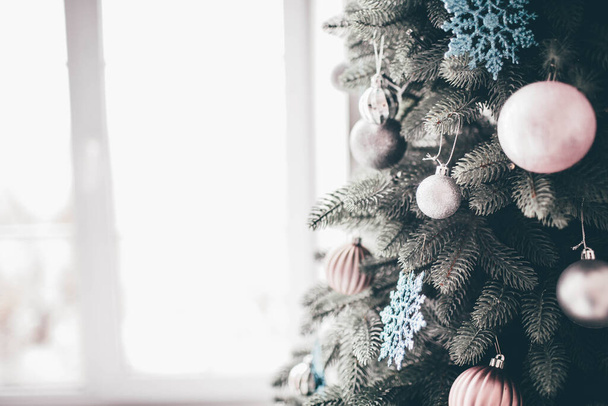 Vicino e vista di taglio di parte decorata di albero di Natale pronto durante tempo di anno nuovo. Decorazioni rosa e bianche tutto intorno all'albero. Luce del giorno
. - Foto, immagini