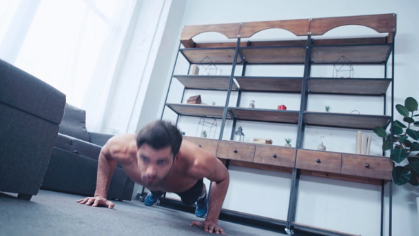 Oberflächenansicht eines hemdslosen Sportlers, der zu Hause Liegestütze auf dem Boden macht - Filmmaterial, Video