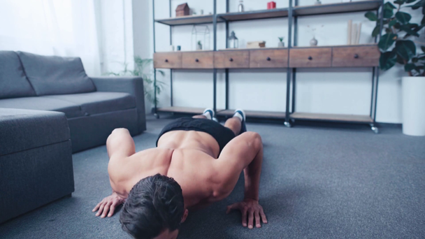 мускулистый, без рубашки спортсмен делает отжимания на полу дома
 - Кадры, видео