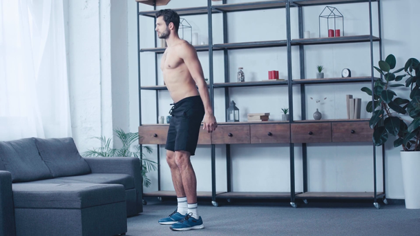 félmeztelen izmos sportoló guggolás edzés közben otthon - Felvétel, videó
