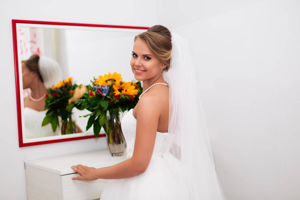 beautiful bride stands by the mirror, admiring herself. - Foto, afbeelding