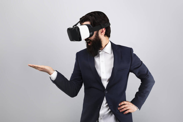 meglepett üzletember VR szemüvegben keres üres kézzel, virtuális valóság koncepció, mock-up kép - Fotó, kép